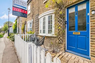 a blue door on a brick house with a fence at Riverside Cottage Retreat Hertford Town Sleeps 6 in Hertford