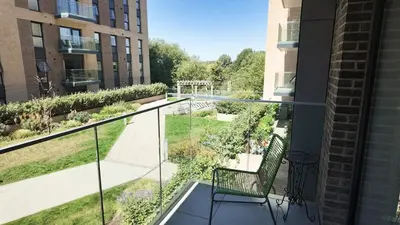 a balcony with a chair looking out at a garden at The Ivy Abode, Stylish 2-Bed Apartment Free Parking in Harlow