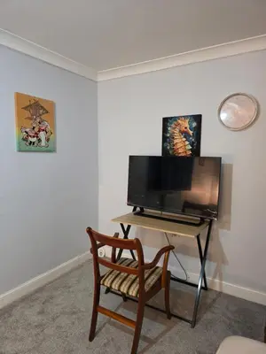 a living room with a desk with a television and a chair at Essex desk chair Free parking WiFi x3 in Hythe