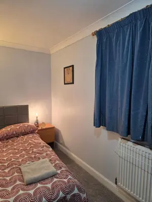 a bedroom with a bed and a blue curtain at Essex desk chair Free parking WiFi x3 in Hythe