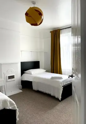 a bedroom with a bed and a yellow curtain at Spacious 4-Bed Home Near Cambridge City Centre in Chesterton