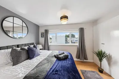 a bedroom with a large bed and a mirror at 3Bed, Sleeps 7, TV in Each Room, Garden, Parking in Basildon