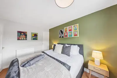 a bedroom with a large bed and a green wall at 3Bed, Sleeps 7, TV in Each Room, Garden, Parking in Basildon
