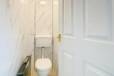 a white bathroom with a toilet and a door at 3Bed, Sleeps 7, TV in Each Room, Garden, Parking in Basildon