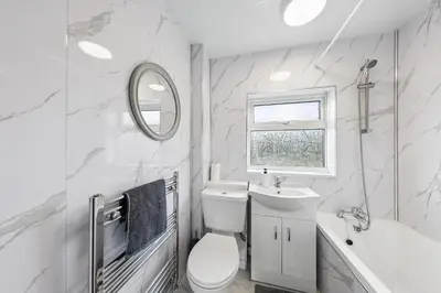 a white bathroom with a toilet and a sink at 3Bed, Sleeps 7, TV in Each Room, Garden, Parking in Basildon