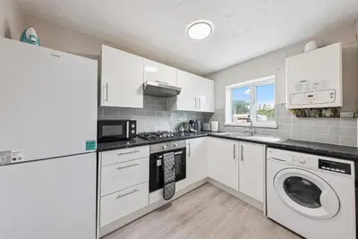 a kitchen with white cabinets and a washer and dryer at 3Bed, Sleeps 7, TV in Each Room, Garden, Parking in Basildon