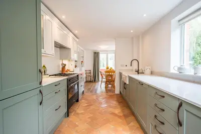 a kitchen with white cabinets and a wooden floor at The Bantams, Monk Soham in Bedfield
