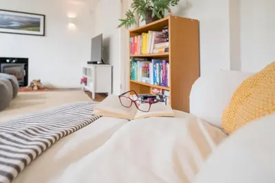a book and glasses sitting on a bed at The Bantams, Monk Soham in Bedfield