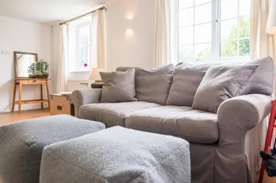 a living room with a gray couch and windows at The Bantams, Monk Soham in Bedfield