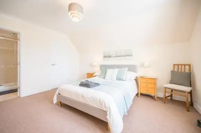 a white bedroom with a bed and a chair at Cosy 4BR Cottage in Great Glemham Village in Great Glemham