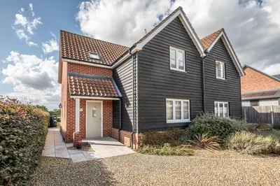 a black house with a white door at Cosy 4BR Cottage in Great Glemham Village in Great Glemham