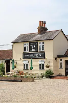 a white brick inn with a sign that reads the white brick inn at The White Hart Inn in Margaretting