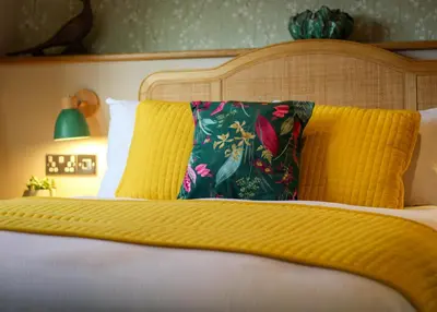 a bed with a yellow blanket and pillows on it at The White Hart Inn in Margaretting