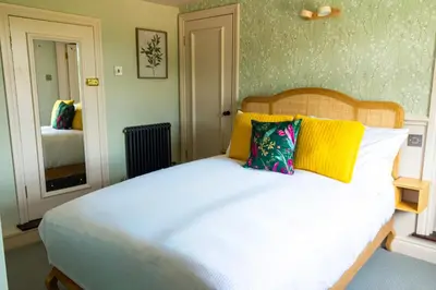 a bedroom with a large white bed with yellow pillows at The White Hart Inn in Margaretting