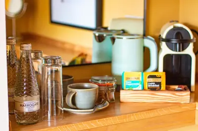 a counter with bottles and cups on a wooden shelf at The White Hart Inn in Margaretting