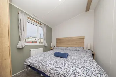 a bedroom with a bed with a blue pillow on it at New - 3 bedroom Caravan, 140 Pasture Lane in Great Clacton