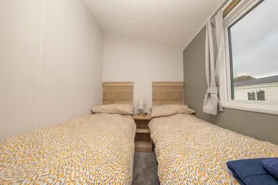 two beds in a small bedroom with a window at New - 3 bedroom Caravan, 140 Pasture Lane in Great Clacton