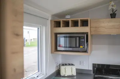 a kitchen with a microwave and a window at New - 3 bedroom Caravan, 140 Pasture Lane in Great Clacton