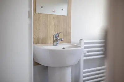 a white sink in a bathroom with a mirror at New - 3 bedroom Caravan, 140 Pasture Lane in Great Clacton