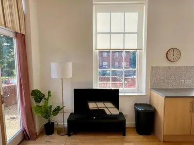 a living room with a table and a clock on a window at Fabulous 2 bed in Leiston in Leiston