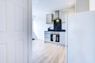 a white kitchen with a stove and a sink at Modern 4 Bed Home with Driveway in Colchester