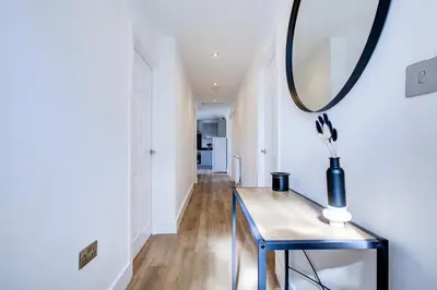 a hallway with a table and a mirror at Modern 4 Bed Home with Driveway in Colchester