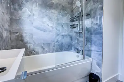 a bathroom with a shower with a tub and a sink at Modern 4 Bed Home with Driveway in Colchester