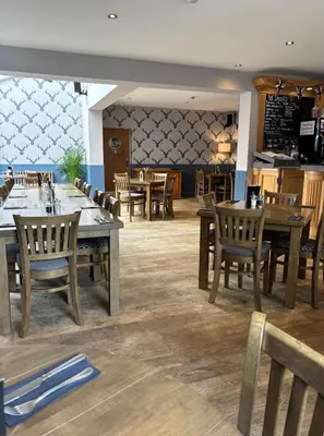 a dining room with wooden tables and chairs at White hart public house in Ashill