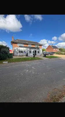 a house on the side of a road next to a street at White hart public house in Ashill
