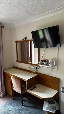 a room with a desk with a television on the wall at Farmhouse Inn in Thaxted