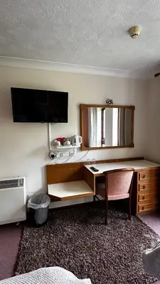 a room with a desk and a tv on a wall at Farmhouse Inn in Thaxted