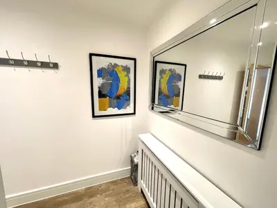 a hallway with two paintings on the wall and a mirror at Modern cosy 2 bed, free parking Bishops Stortford in Bishops Stortford