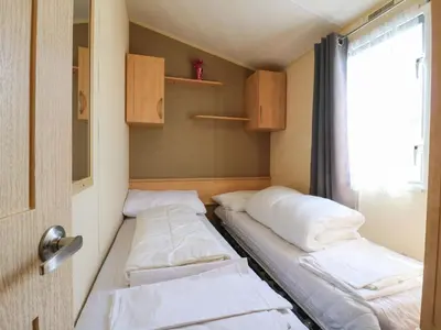 two beds in a small room with a window at Singh Leite & Luisa Family Caravan in Clacton-on-Sea