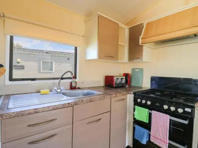a small kitchen with a sink and a stove at Singh Leite & Luisa Family Caravan in Clacton-on-Sea