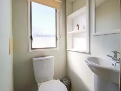 a bathroom with a toilet and a sink and a window at Singh Leite & Luisa Family Caravan in Clacton-on-Sea