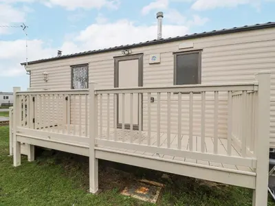 a mobile home with a wooden porch and a fence at Singh Leite & Luisa Family Caravan in Clacton-on-Sea