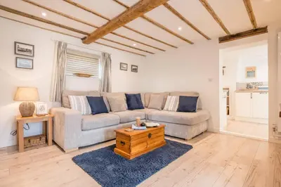 a living room with a couch and a table at 2 Beach Cottages, Thorpeness in Thorpeness