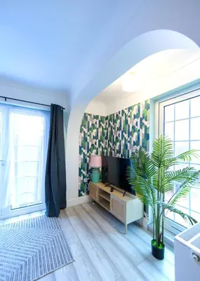 a living room with a tv and a plant at Bright & Airy 4x Bed House with Parking in Ely