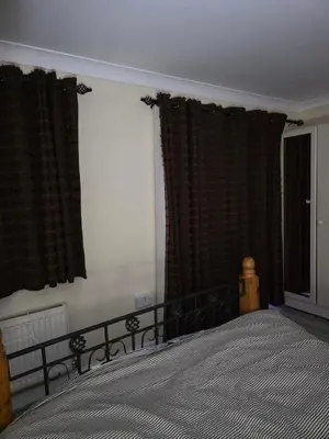 a bedroom with a large bed and curtains at Cosy in Colchester x5 in Hythe