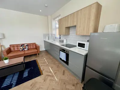 a kitchen with a refrigerator and a couch in it at 4 The Royal Serviced Apartments, Harwich - Garden- Parking-Fast WiFi in Parkeston