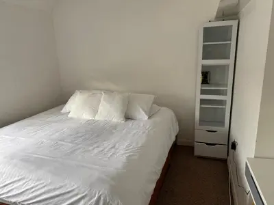 a bed with white sheets and pillows in a bedroom at 3-bedroom family home with large garden and free parking in Loughton