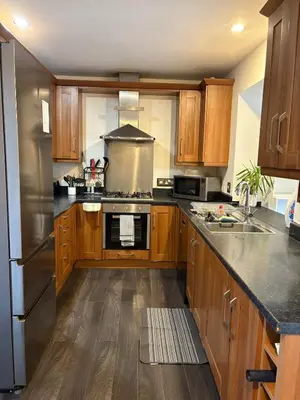 a kitchen with wooden cabinets and stainless steel appliances at 3-bedroom family home with large garden and free parking in Loughton
