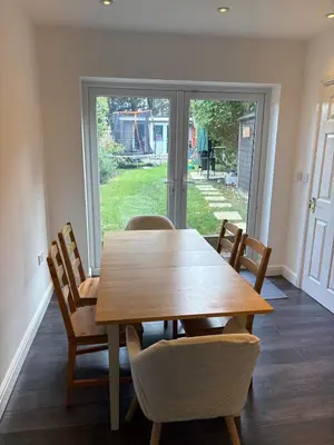 a dining room with a wooden table and chairs at 3-bedroom family home with large garden and free parking in Loughton