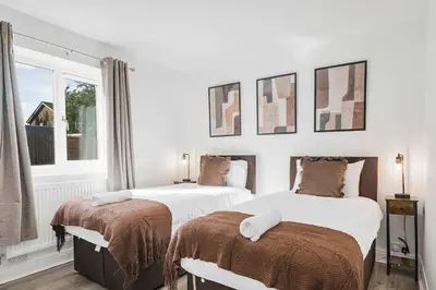 two beds in a bedroom with white walls and a window at Modern Comfort 4BR House in Colchester