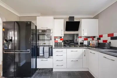a kitchen with white cabinets and a black refrigerator at Modern Comfort 4BR House in Colchester