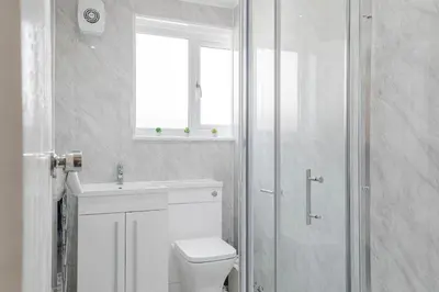 a bathroom with a toilet and a sink and a window at Modern Comfort 4BR House in Colchester