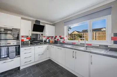 a kitchen with white cabinets and a large window at Modern Comfort 4BR House in Colchester