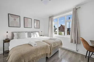 a white bedroom with a large bed and a window at Modern Comfort 4BR House in Colchester