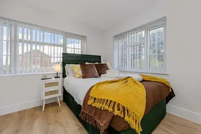 a bedroom with a bed with a yellow blanket on it at Cosy and Peaceful flat in Benfleet close to station in South Benfleet