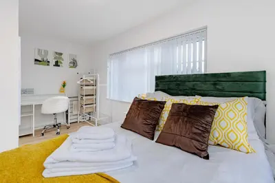 a bedroom with a bed with a green headboard at Cosy and Peaceful flat in Benfleet close to station in South Benfleet